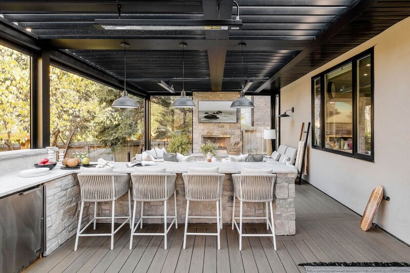 An outdoor bar with stone accents, rattan stools and black pendant lighting. 