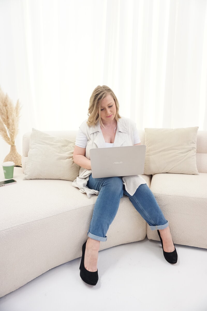 Female Operations Consultant sat on a comfy chair working on her lapop