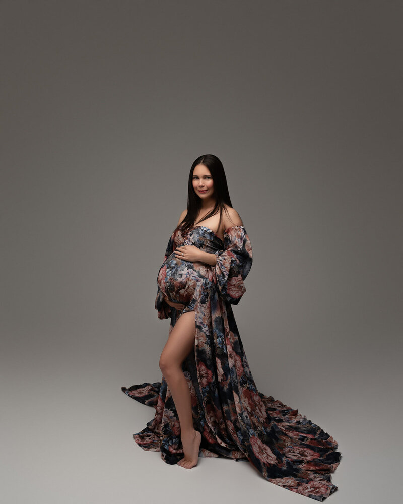 Long-sleeved maternity dress in navy floral print with a high slit – posed in studio lighting
