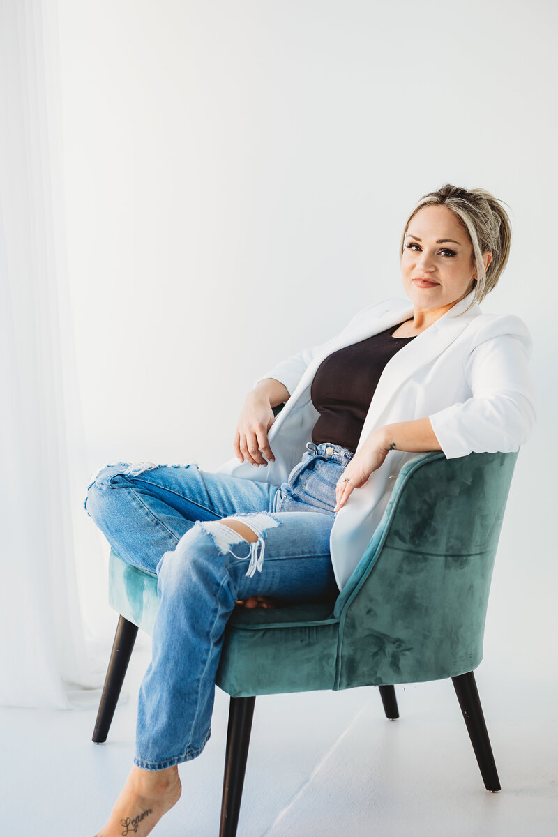 Business woman in white blazer and jeans sitting on the floor