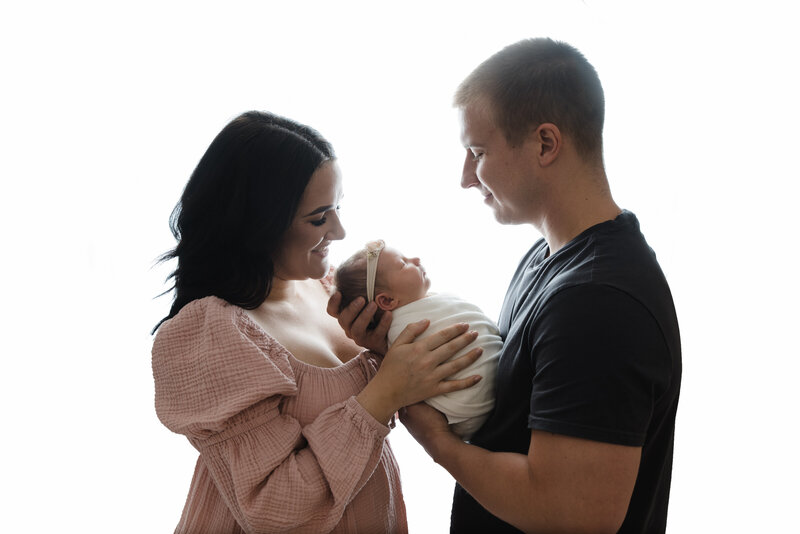 mom and dad holding baby girl for a backlit picture