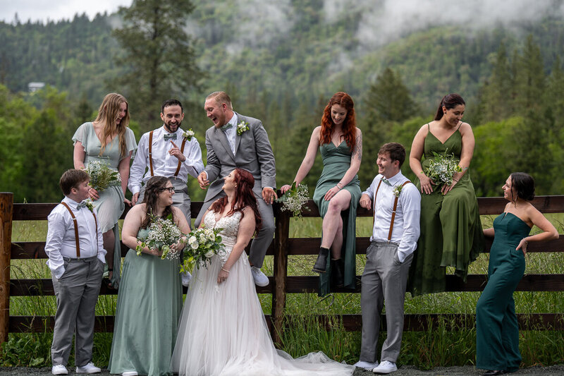 wedding party in oregon sitting on a fence and talking