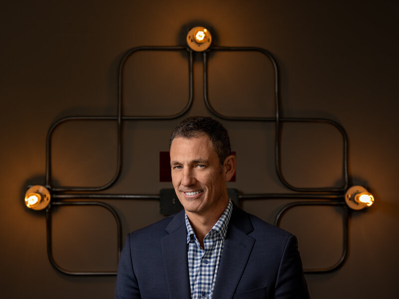 A man smiling in front of an industrial style light