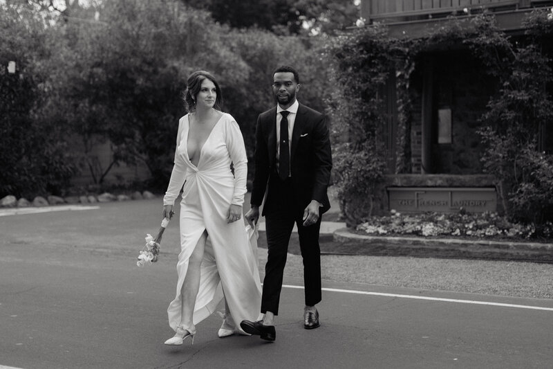 A candid black and white wedding portrait of a bride and groom walking together, exuding timeless elegance. We capture authentic love stories with a fine art documentary approach, specializing in natural, luxury wedding photography.