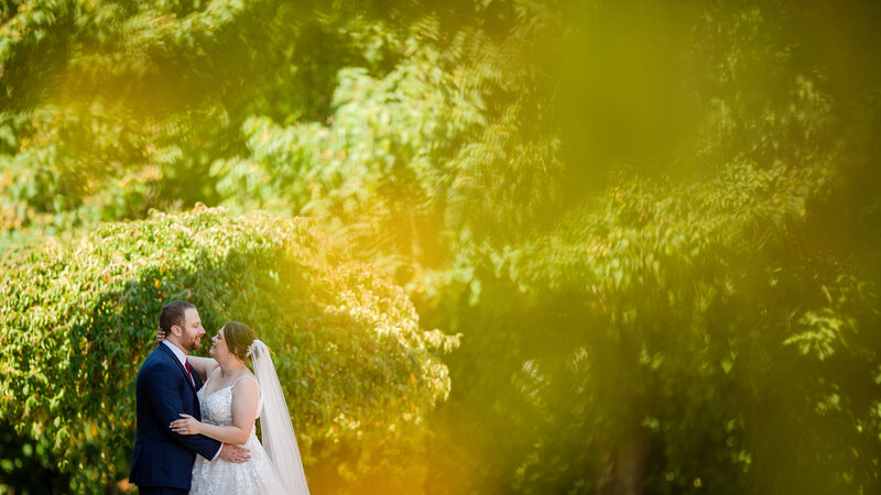 Vibrant summer wedding moment with a couple enjoying the greenery outside the Phoenixville Foundry.