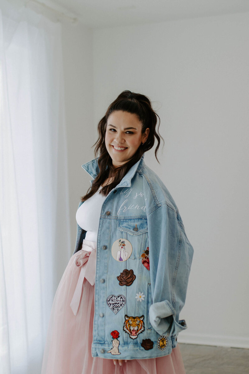 woman with dark hair in jean jacket and pink skirt