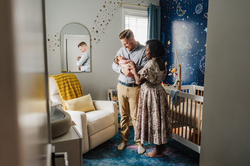 parents look at new baby in planet themed nursery