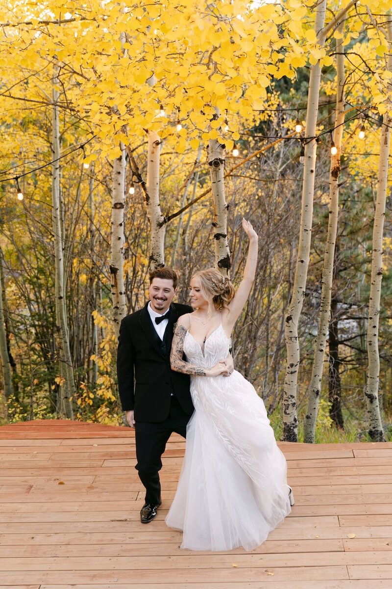 Bride and groom dancing beneath yellow aspen trees during their fall Colorado wedding at Wild Basin Lodge.