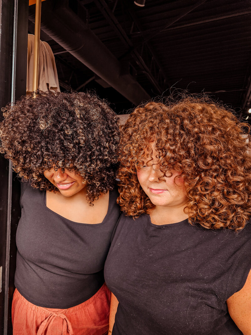 Two different clients at Moxie by KC show off their big beautiful curly hairstyles from our talented artists