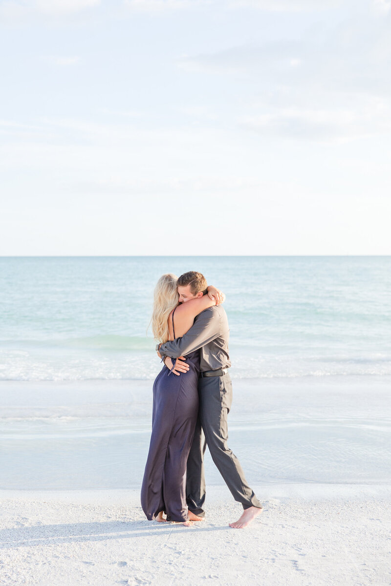 engaged couple hugging on the beach