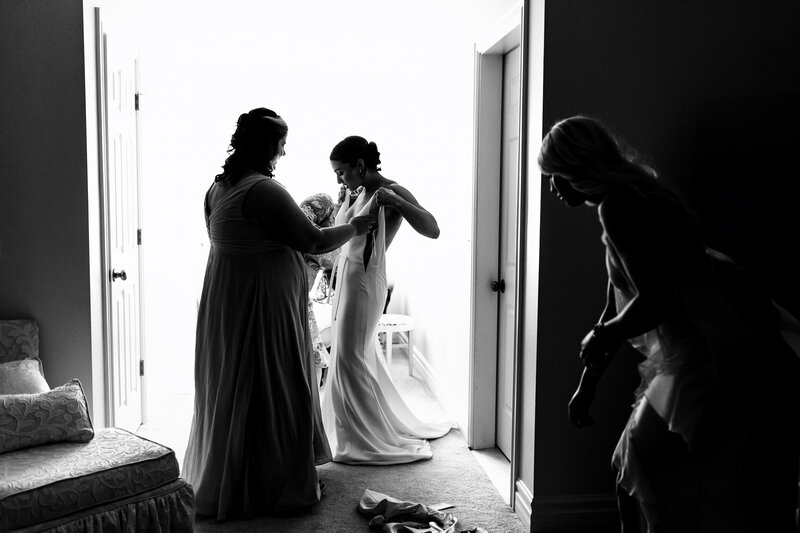 A mother helps her daughter into her wedding dress before the ceremony