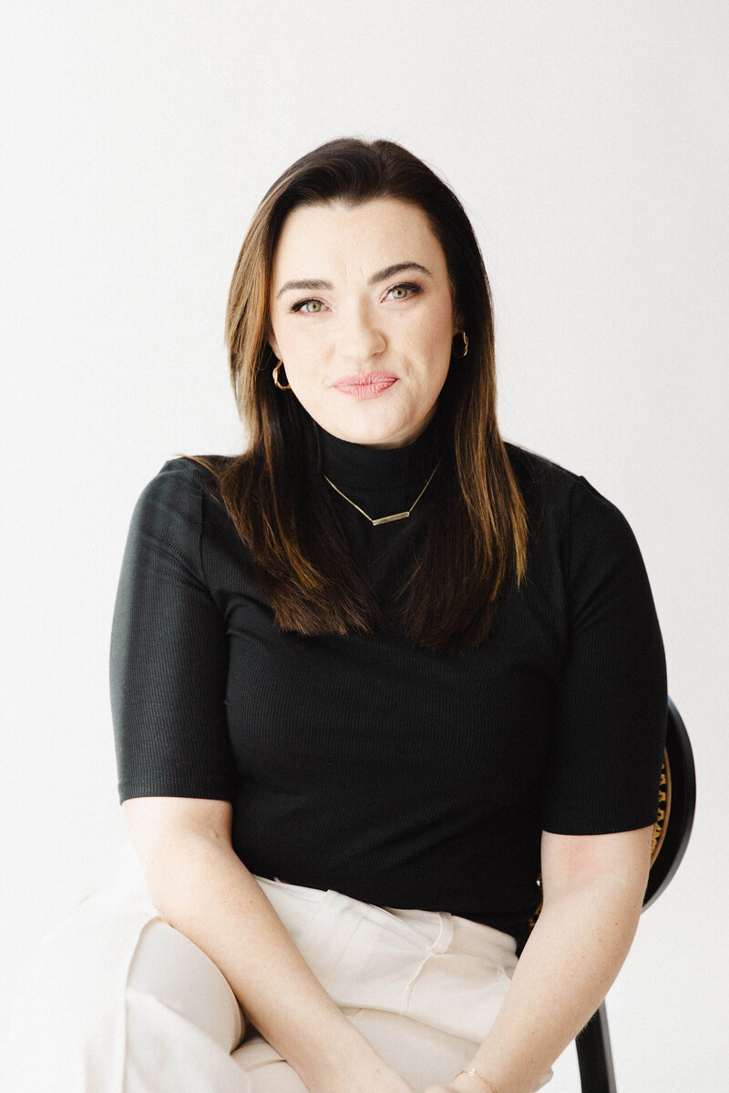 Brunette woman with black turtleneck shirt grinning