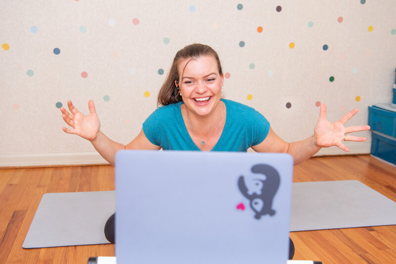 A female physical therapist cheering on her client during a virtual physical therapy session.