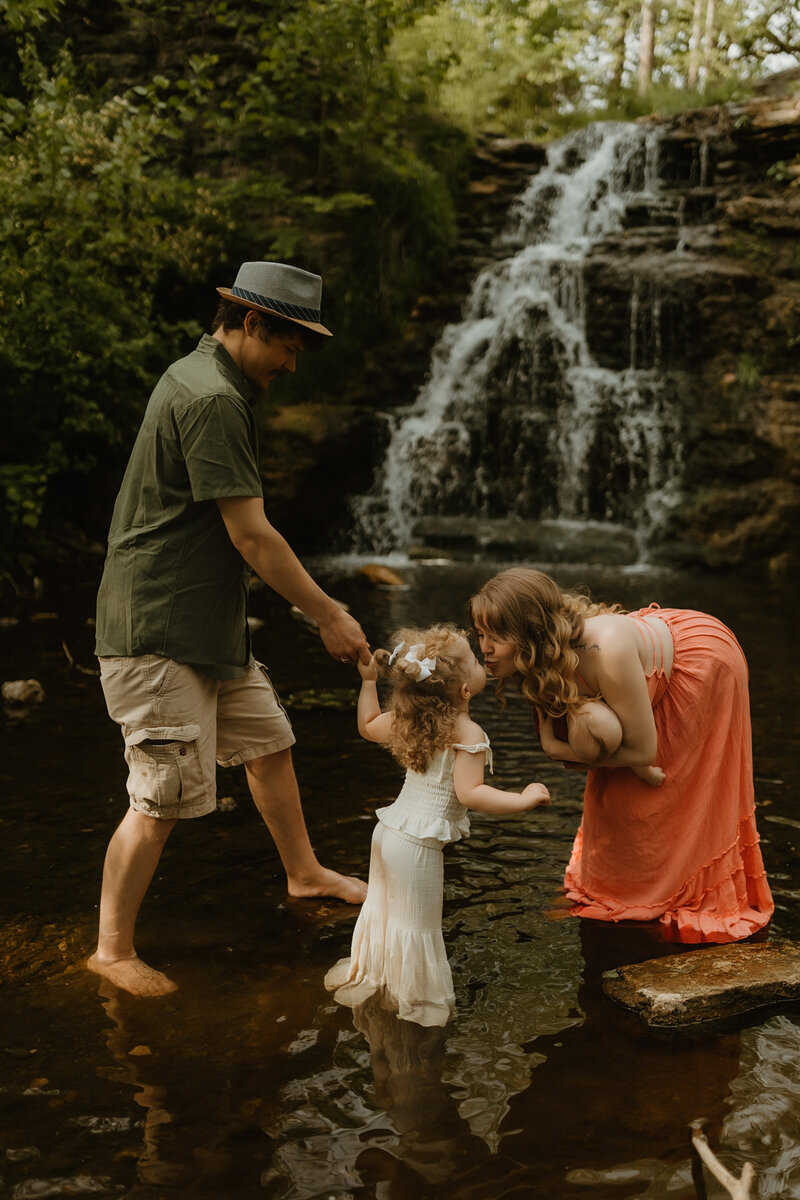family playing in a creek near an indiana waterfall