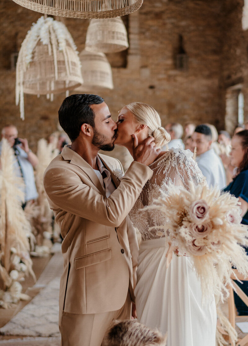 Sortie de cérémonie laïque au Domaine du Manoir de Chivré dans le Calvados, les mariés s’embrassent juste après s’être dit oui lors de leur mariage mixte – capté avec émotion par un duo photographe vidéaste