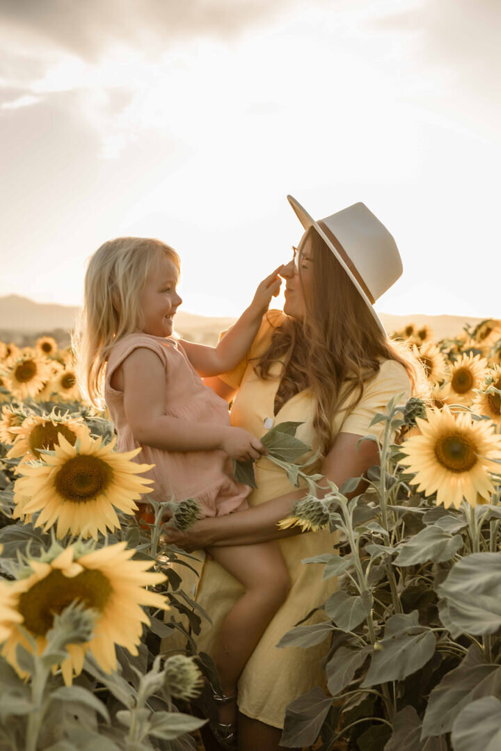 Sunflower Family Photography Session with Blury Photography, a mother holding her daughter in the glow of golden hour