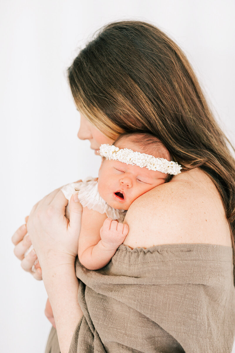 Springfield MO newborn photographer captures mom holding sleeping baby girl in floral crown