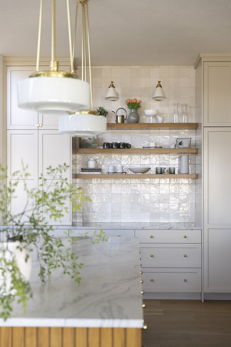Bright modern San Diego kitchen with open shelving, marble countertops, and warm accents, representing the style of homes buyers can find in the San Diego real estate market — Mary Pernicano Real Estate.