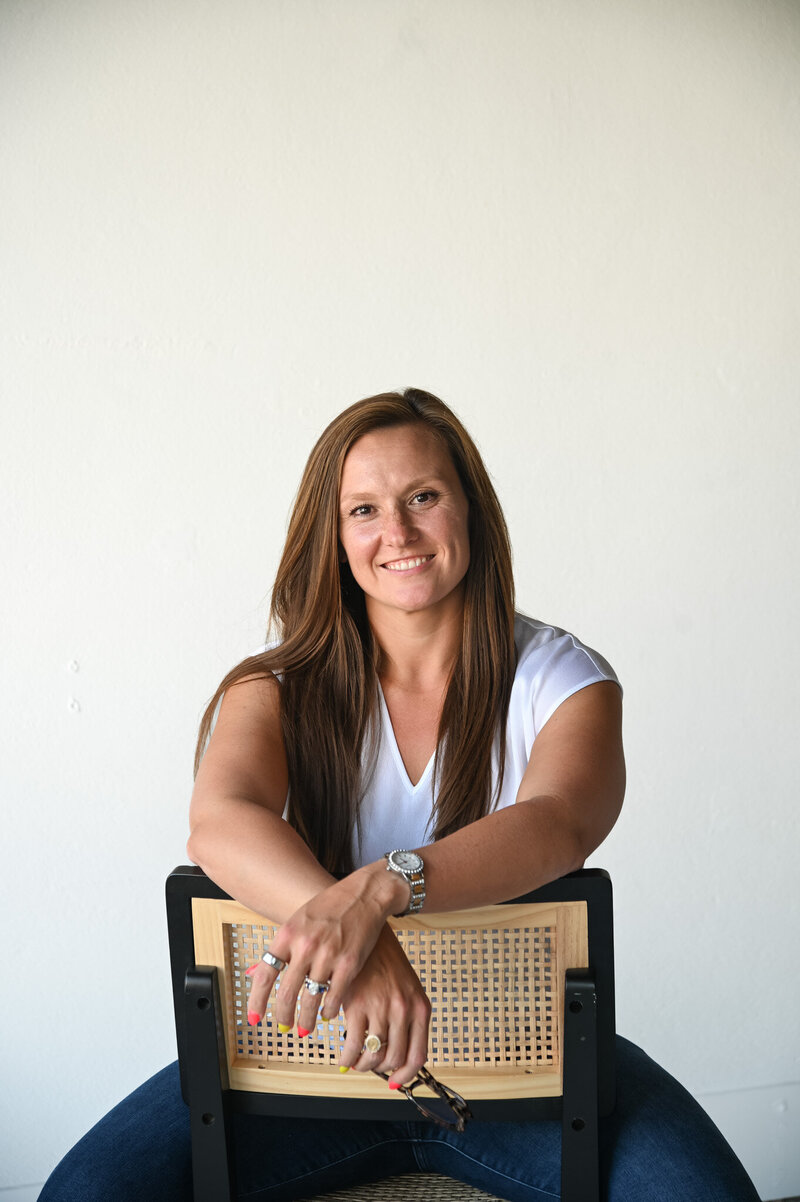 Hannah Short sitting on a chair and smiling beside text introducing her as a therapist who understands disordered eating through lived experience at Rooted & Nourished Psychotherapy