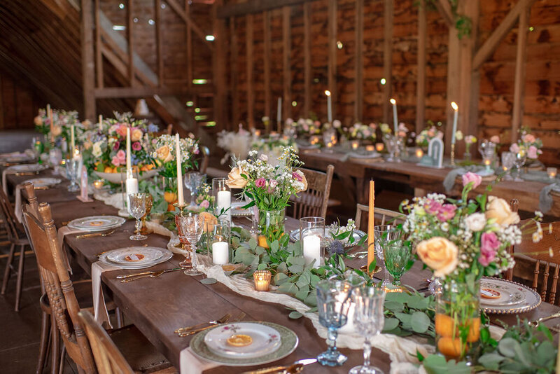 Long wooden wedding tables decorated with flowers and candles
