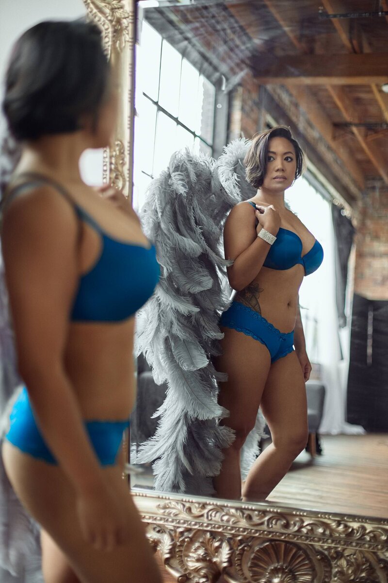 Woman staring at her reflection on a luxury mirror wearing lingerie and angel wings