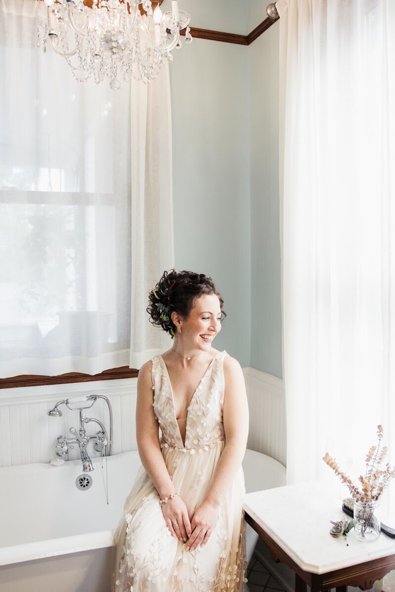 bride in white dress smiling in a bathroom