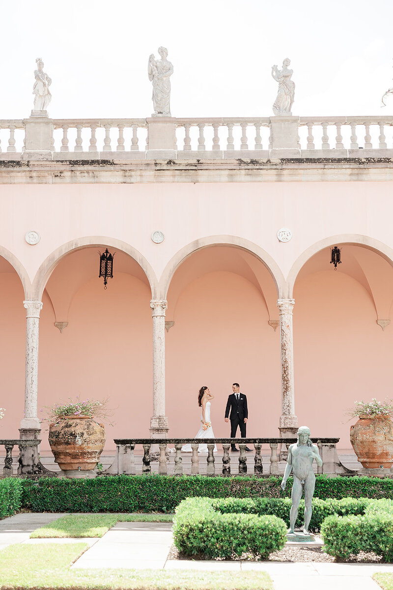 Bride and groom in walking through arched pink hallways at a Ringling Gardens 