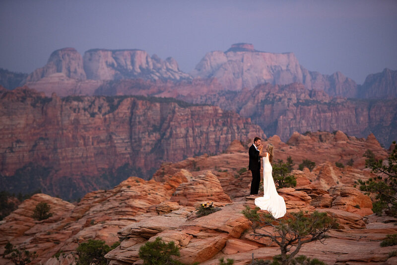bride and groom standing on the rocks of Zion National Park. The West Temple  mountain feature as the backdrop of their wedding vows.