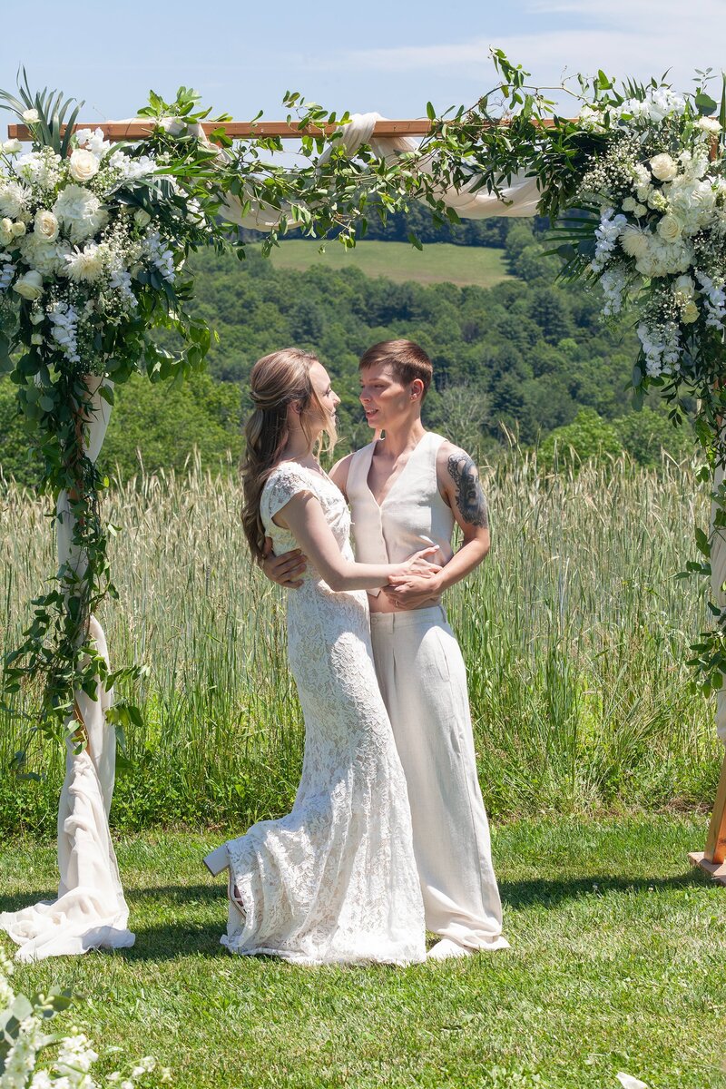 Couple standing under a floral wedding arch