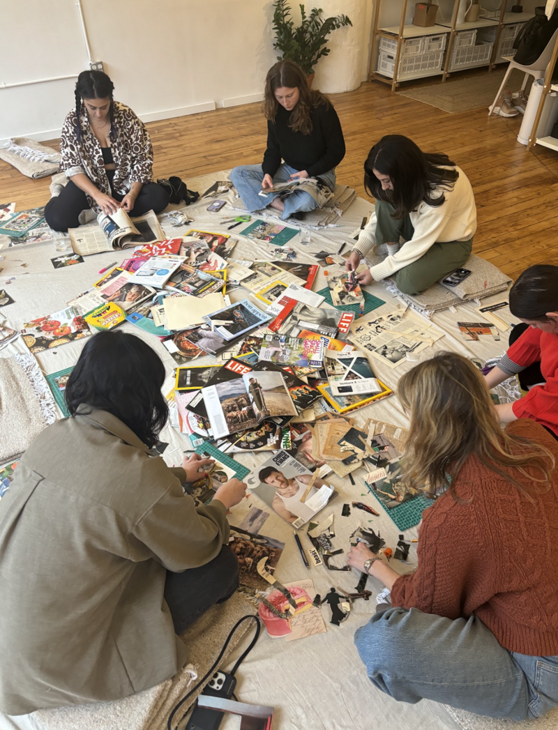 Collective members sitting on the floor with several magazines collaging