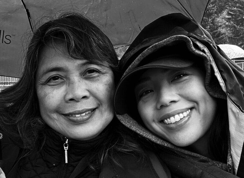 Christelle and her mom in black and white in the rain under an umbrella