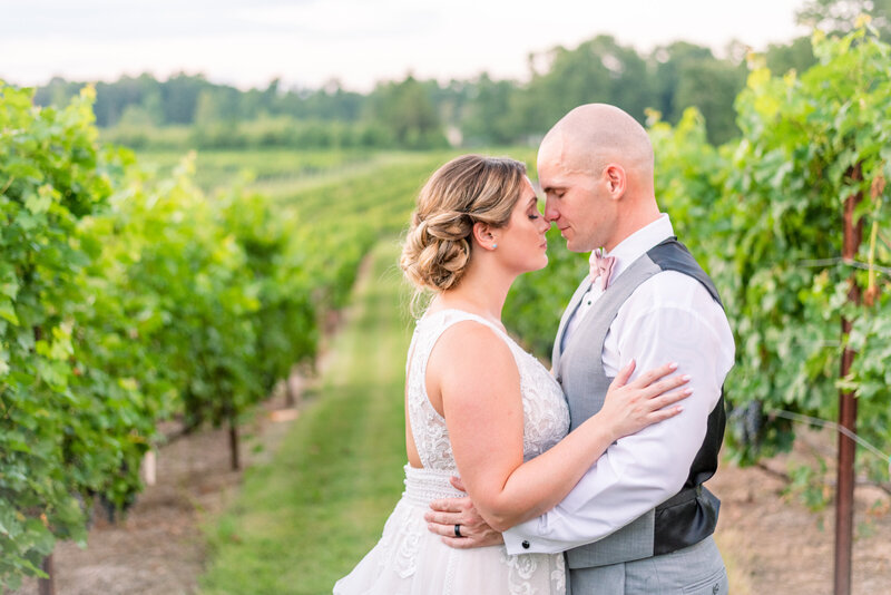 Ashleigh and Patrick walk the vineyard of their wedding venue, for a quiet moment resting their foreheads on each other