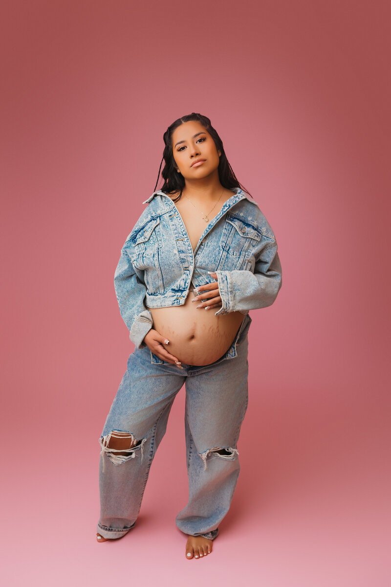 jean on jean outfit for maternity portraits on a pink backdrop in phoenix maternity studio