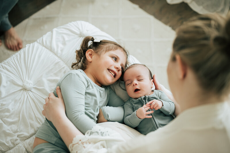 two sisters on bed with baby brother