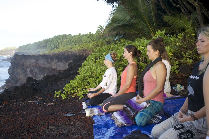 Hawaii YTT students meditating on the beach overlooking the Pacific ocean
