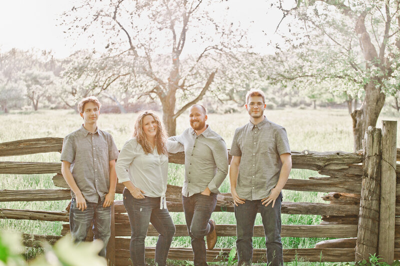 A joyful moment between mother and sons, captured in natural light and surrounded by nature.