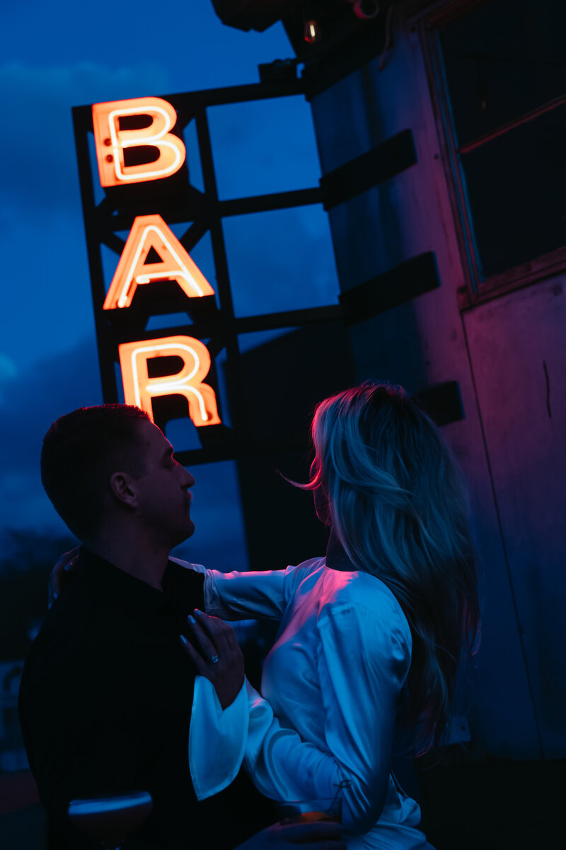 couple in front of neon bar lights