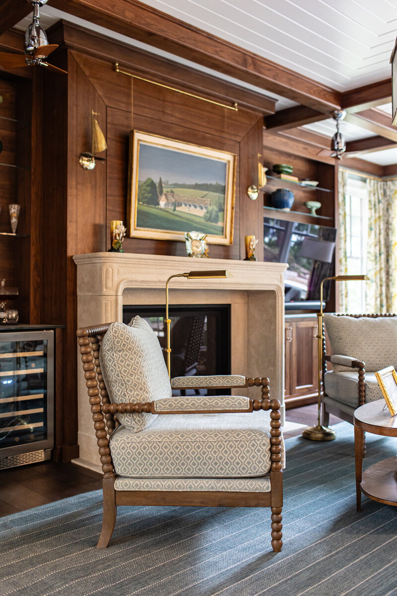A magazine-worthy editorial shot featuring a contemporary fabric-covered wood chair in a stylish sitting room. The space is highlighted by dark wood paneling on the walls and a crisp white ceiling, creating a striking contrast and sophisticated ambiance.
