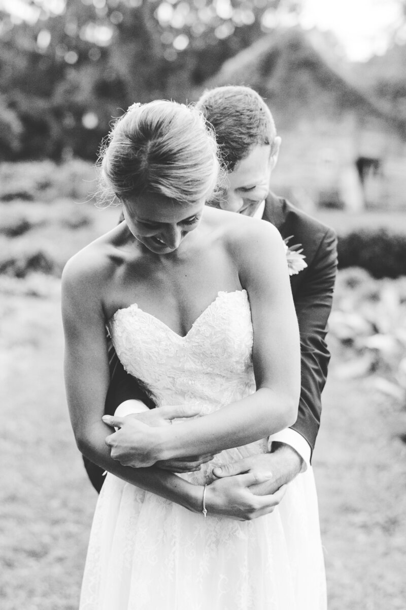 black and white photo of groom embracing bride from behind