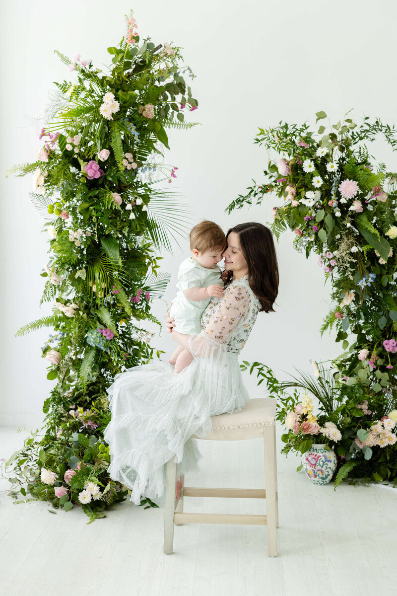 Mom holding son with an arbor of flowers  for mini model rep program