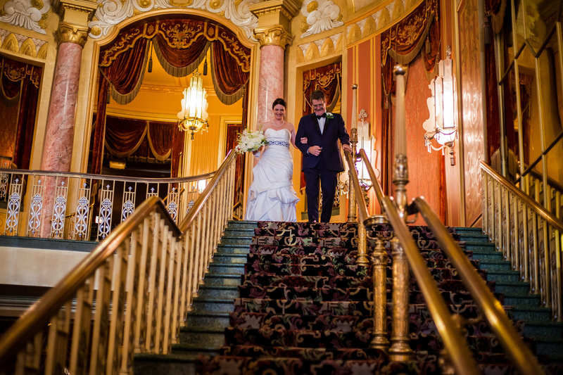 Father escorts bride down the grand staircase at the Warner Theatre