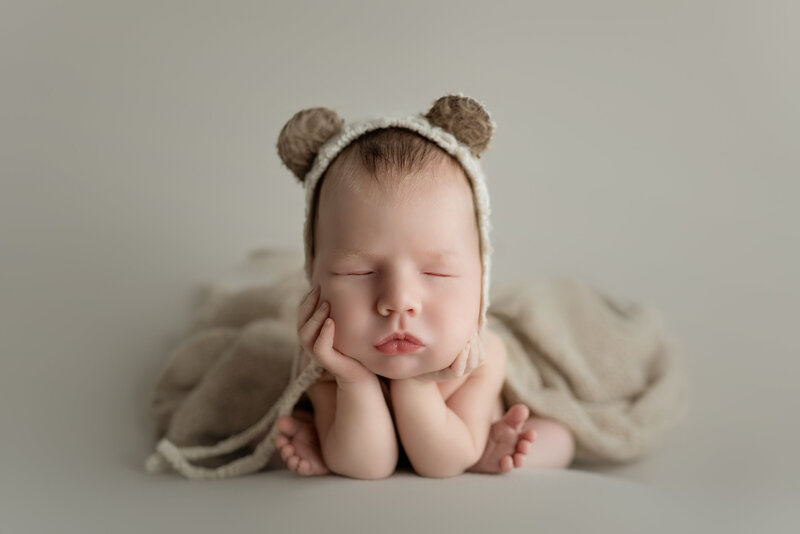 Froggy pose newborn portrait with bear bonnet and neutral wrap, photographed in Paris, Ontario.
