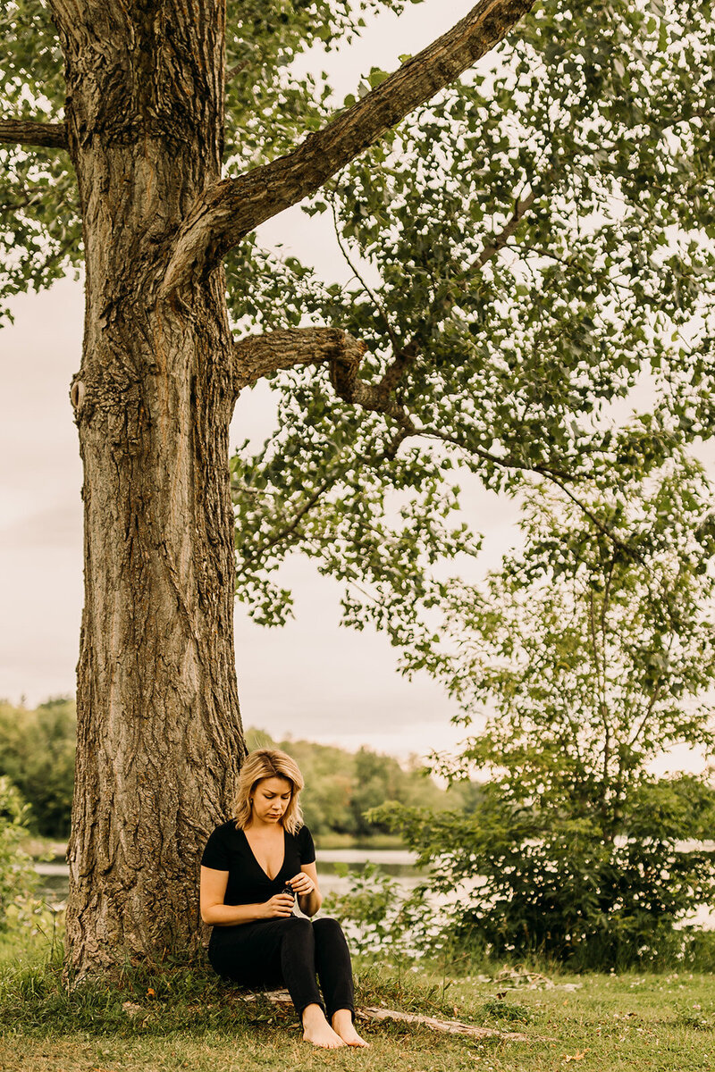 A woman sits beneath a tree.