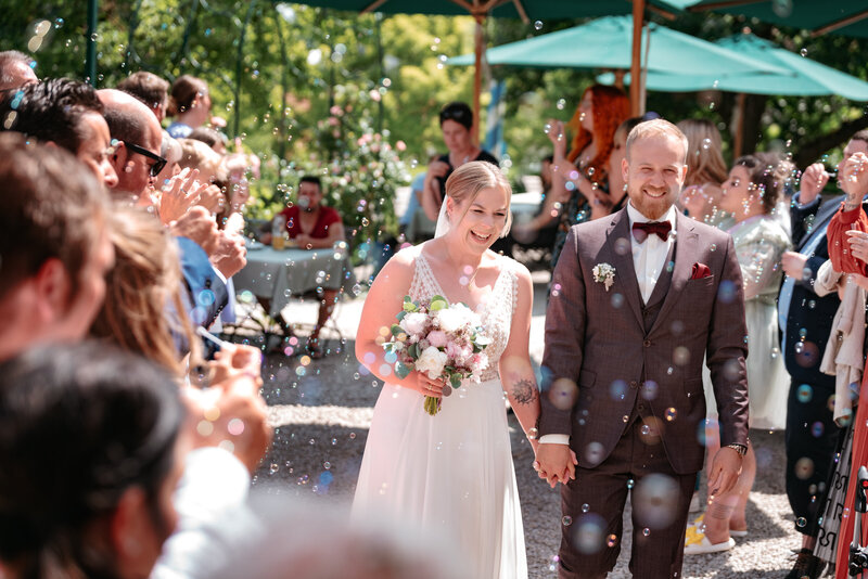 Einzug des Brautpaars an der  Location mit Seifenblasen und glücklichen Gäasten