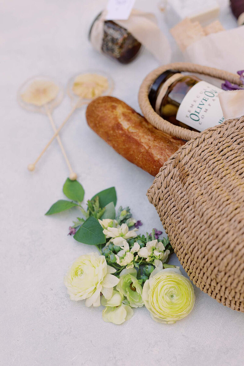 19-radiant-love-events-flatlay-picnic-basket-with-floral-honey-bread-olive-jar-delicately-sprawled-out-romantic-elegant-timeless