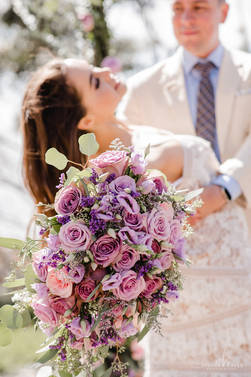 bride smiling up at groom while holding large bridal bouquet