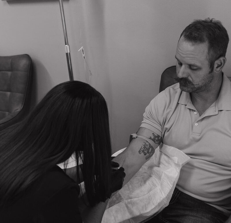 A black and white photo of a nurse putting an IV in a man.