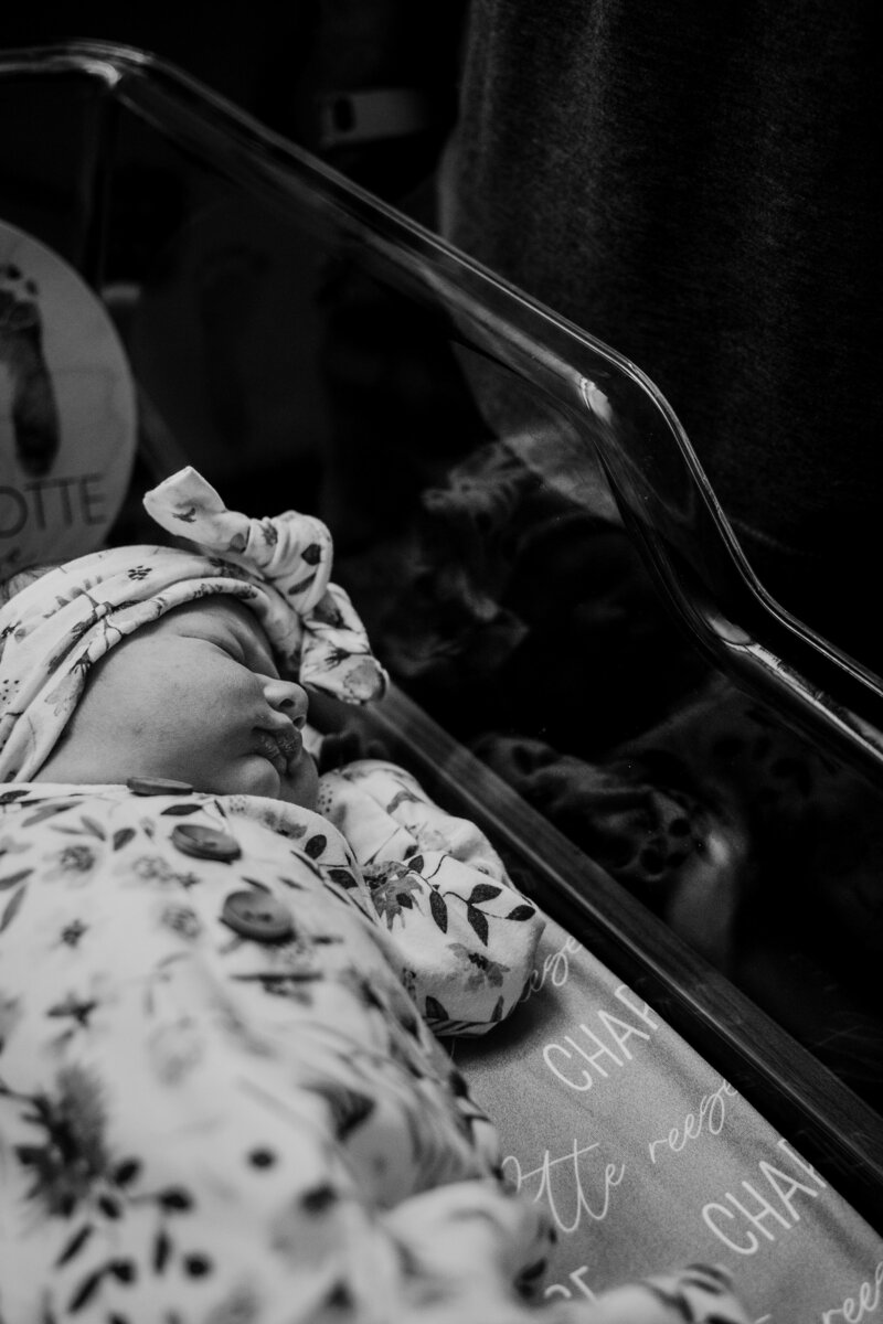 Black and white photo of baby laying in hospital bassinet for Fresh 48 session photographed by Bethany Simms Photography