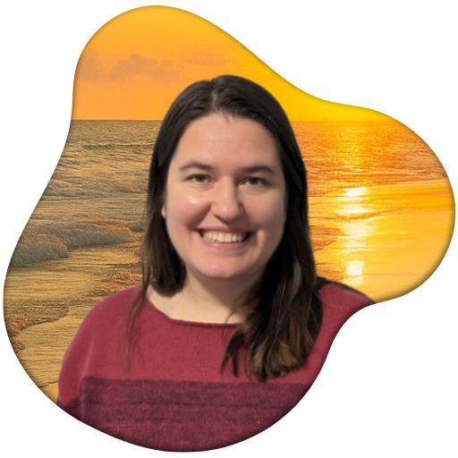 A photo of the travel agent, a smiling woman with brown hair featured in front of a warm ocean sunset.