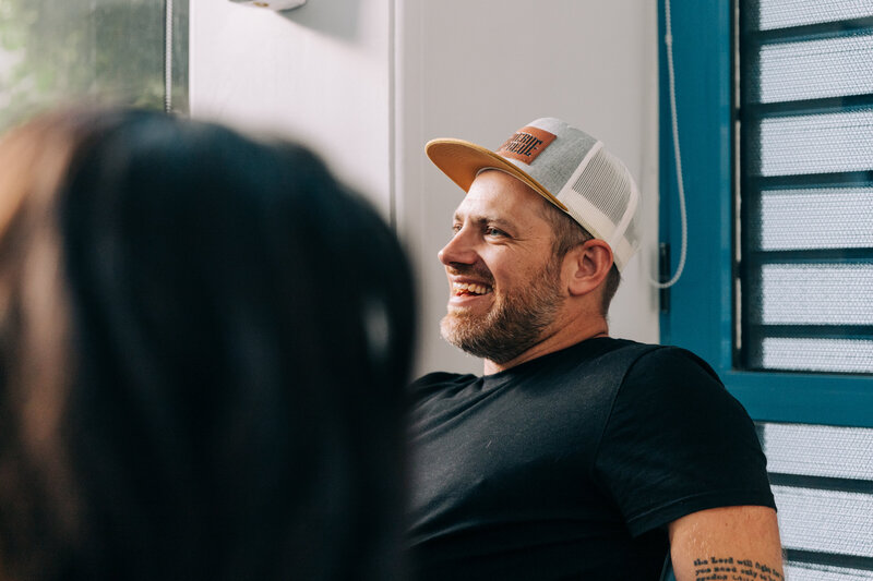 A man in a baseball hat laughs